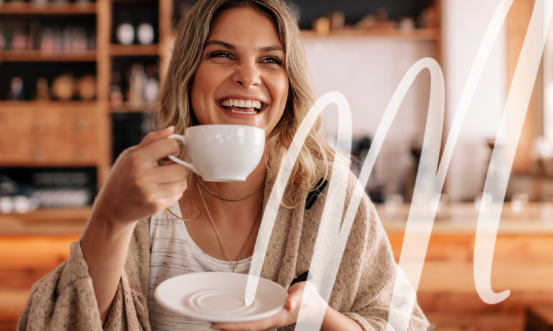 woman laughs as she is about to drink her coffee