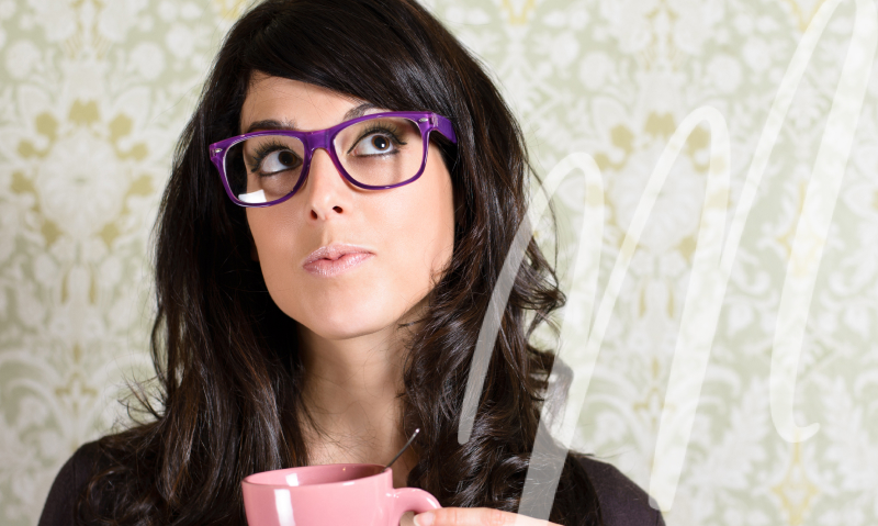 woman in purple glasses looks up from her pink coffee cup